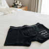 Groom's personalised boxer shorts laid out on a bed on the wedding morning. The black cotton boxer shorts feature custom text, making them a perfect groom gift or detail shot for wedding photography.