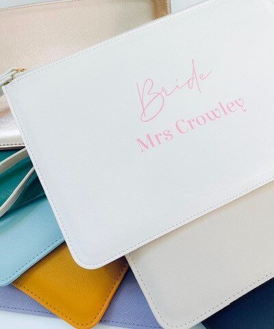 Personalised faux leather clutch bags in multiple colours with custom name text – ideal gifts for brides, bridesmaids, and the bridal party.