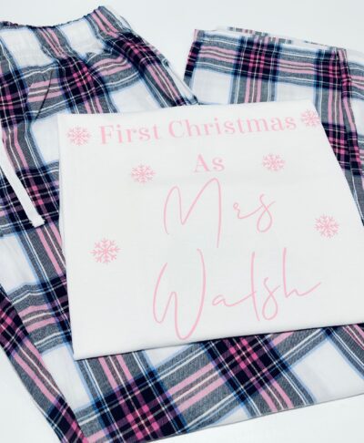 Personalised First Christmas long pyjamas with married name and snowflake design, folded with plaid bottoms – ideal newlywed Christmas gift.