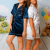 Two children wearing personalised satin short pyjamas in navy and white