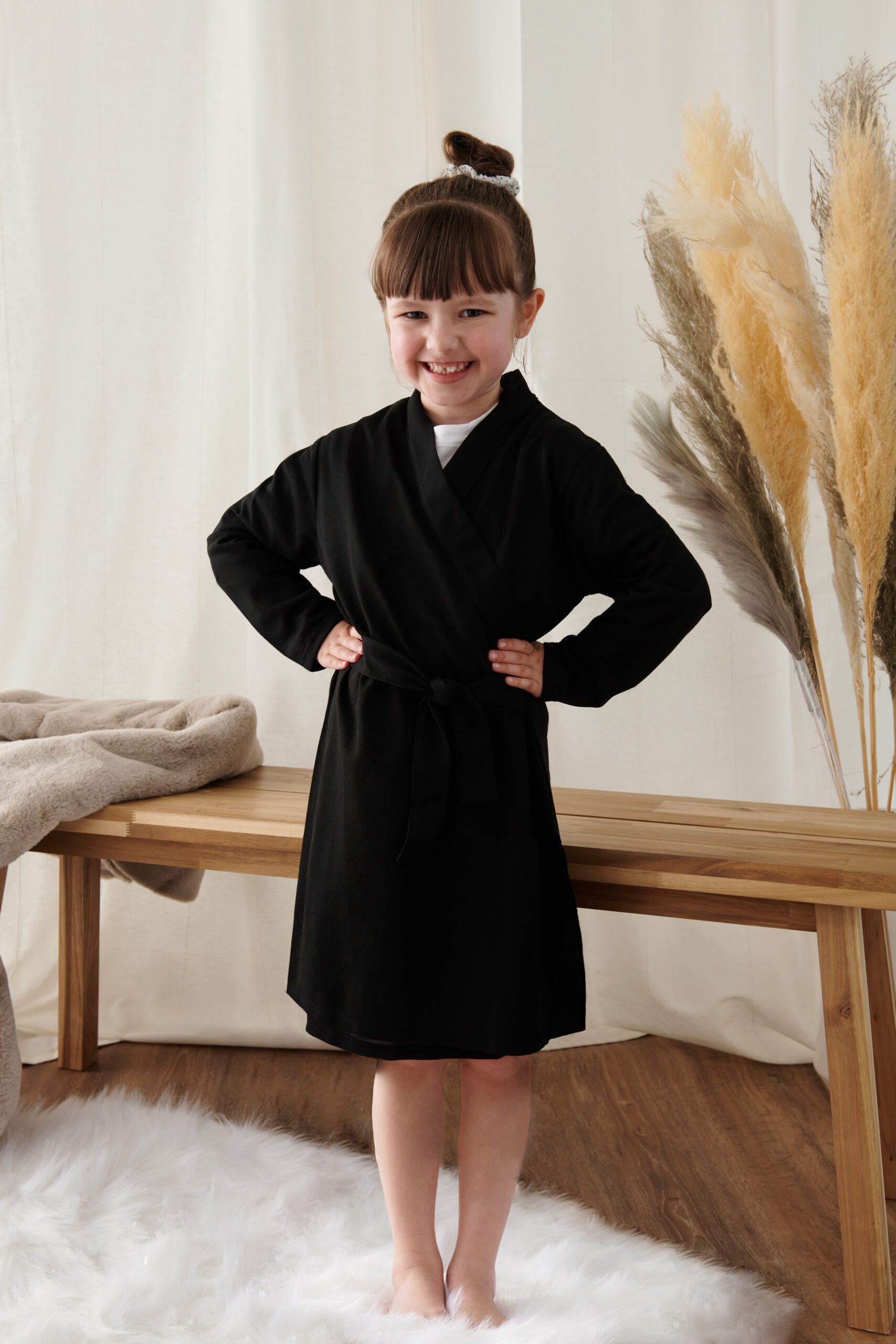 Smiling child wearing a black personalised cotton robe – perfect for flower girls, page boys, or junior bridesmaids on the wedding morning.