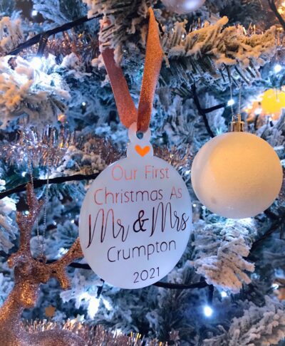 Personalised Christmas bauble reading “Our First Christmas As Mr & Mrs” with surname and year, hanging on a festive Christmas tree.